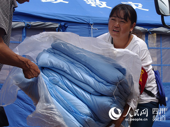 田慶美正在給村民發放棉被。（陳永斌攝）
