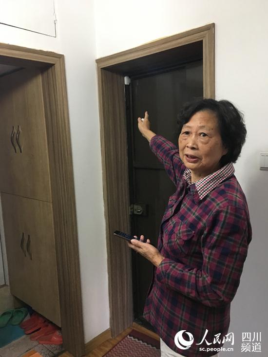 71岁的万天禄老人家介绍着家里门口处安装的安防设备.