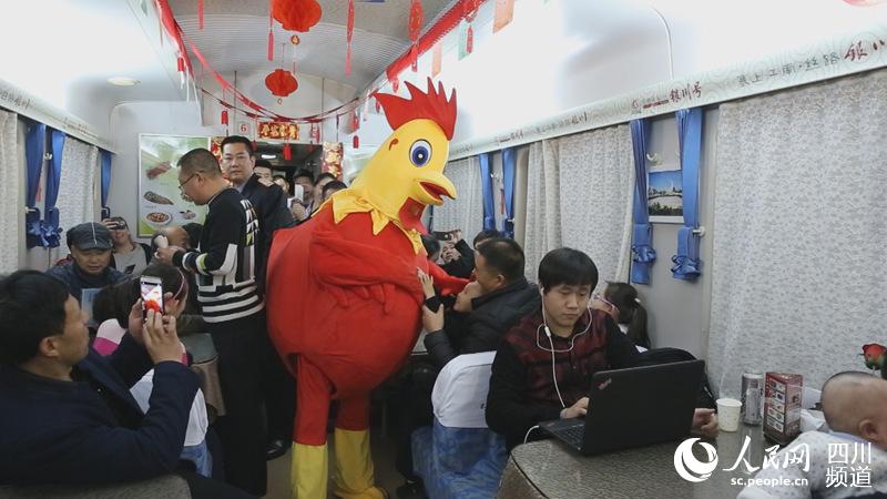 K1085次列车工作人员装扮的大公鸡与旅客互动。（图片由兰州铁路局提供）