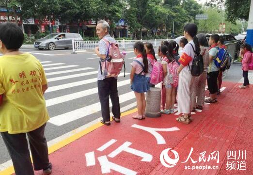放学时段,龙马潭区玉带河交通路口处,学生在"行人等候区"等待通行.
