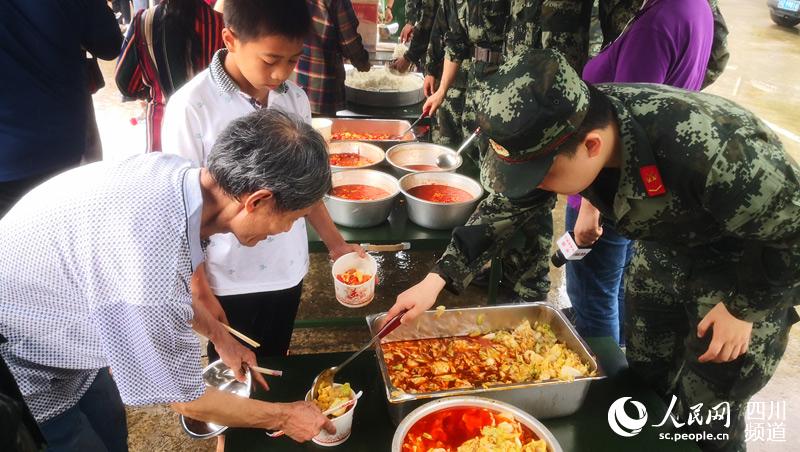 6月19日中午，四川省宜賓市長寧縣雙河鎮安置點，受災群眾吃上了豐盛的飯菜。圖為受災群眾正在打菜。（人民日報記者宋豪新 攝）