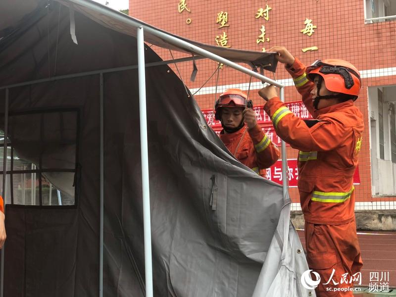 四川省森林消防總隊消防員在長寧縣雙河鎮中學為受災群眾搭建帳篷。（柏龍 攝）