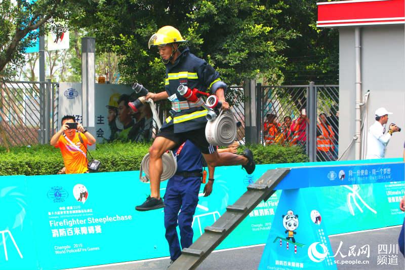 一位参赛队员提着救援设备跃过障碍物。（刘浏 摄）