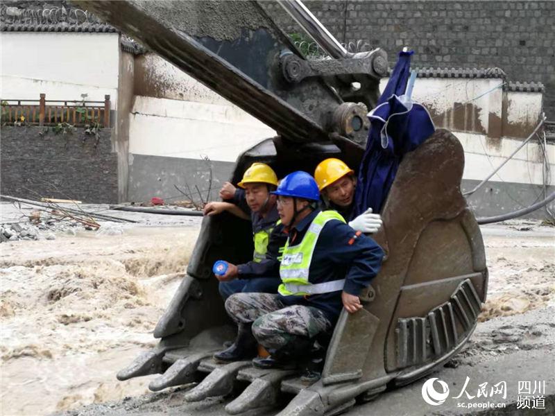 中国电信抢险人员通过挖掘机过河抢修通信。