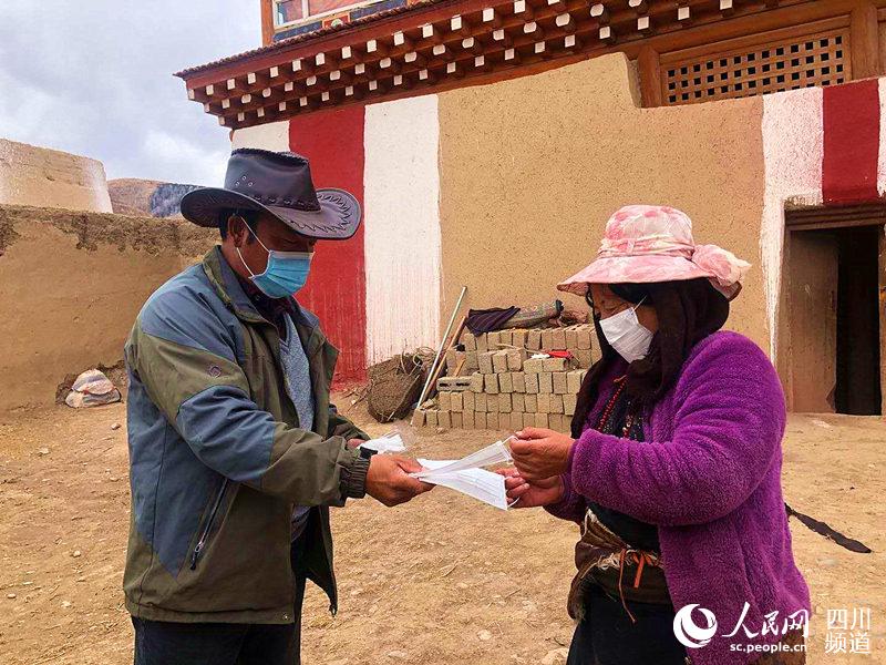 一位藏族同胞接過工作人員送來的口罩。澤花羅日 攝