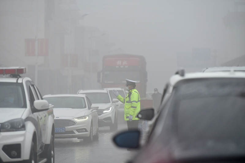2020年2月9日，涼山州西昌市，大霧中的交警在普詩鄉疏導車輛行駛。（吉木木且 攝）