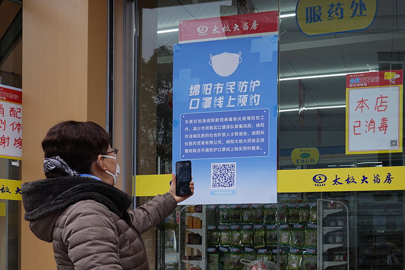 2020年2月10日，綿陽市城區，一市民掃碼預購口罩。（林明 攝）