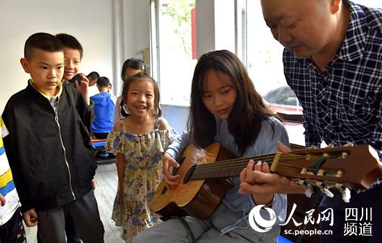 托管中心里，一名辅导老师正在辅导留守儿童弹吉他。苏忠国 摄