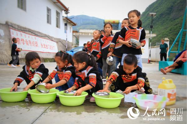 美姑縣洛俄依甘鄉新農村幼教點的孩子們飯后自己洗碗。人民網 朱虹 攝