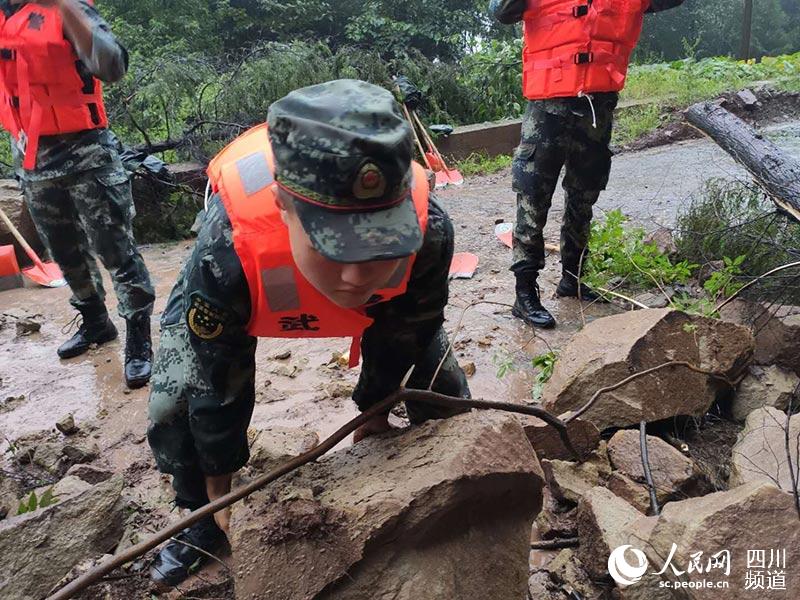 武警官兵前往營山縣雙流鎮途中路遇落石，救援官兵搬運石頭，清理障礙。