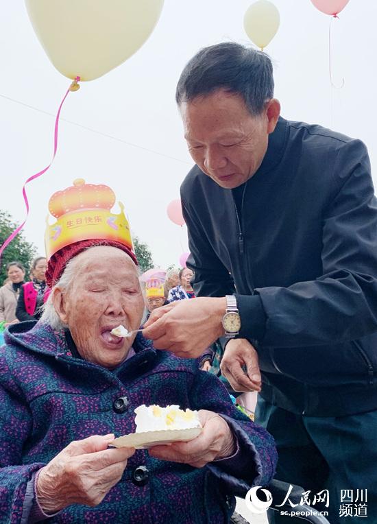 村“兩委”工作人員喂老人吃蛋糕。青白江新聞中心供圖