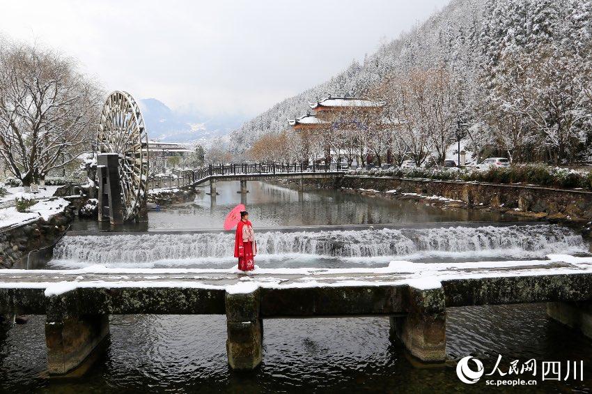 1月28日，涼山州越西縣水觀音景區。一位紅裝女子走在雙石古橋上，與周圍的雪景相映成趣。王德宏攝