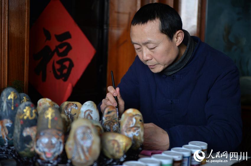 雷文彬正在創作石頭畫。王斌攝