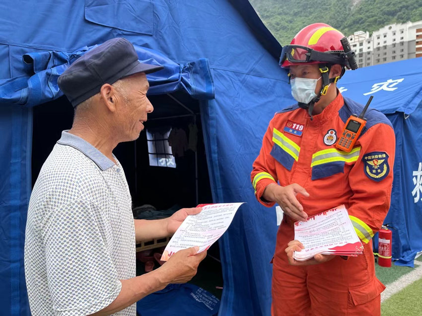 消防員發放“安置點消防安全十提示”。四川省消防救援總隊供圖