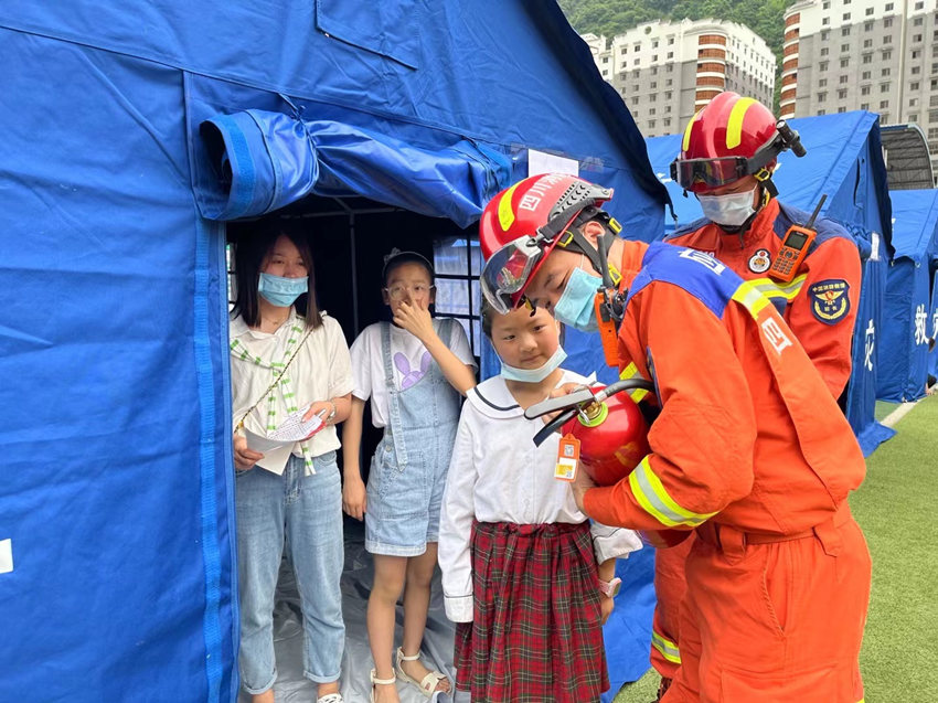 消防员向小朋友讲解灭火器的使用方法。四川省消防救援总队供图