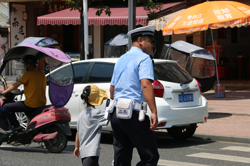 成都交警九分局民輔警頂著烈日護送小朋友過馬路。四川省公安廳供圖