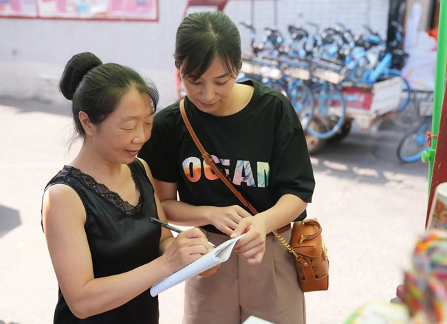 中江县烟草服务人员王凌正与涂绘琼沟通经营策略。中江县烟草公司供图