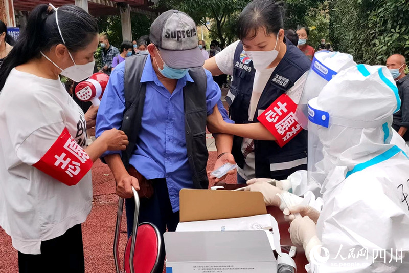 志願者攙扶老人去登記信息。柯娟攝