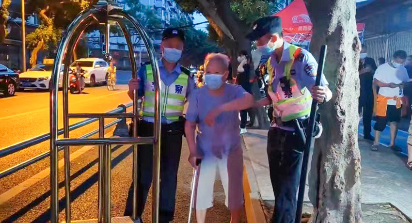 执勤民辅警将人行道上一名行动不便的老人搀扶至核酸检测点。武侯区公安分局供图