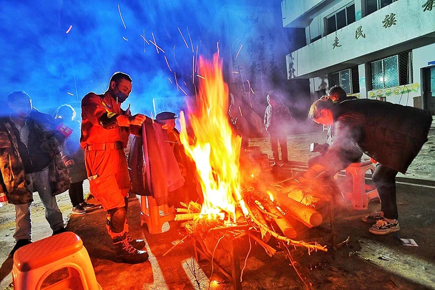 9月5日深夜，消防救援人員在燕子溝鄉排查時烤干衣服。四川省消防救援總隊供圖