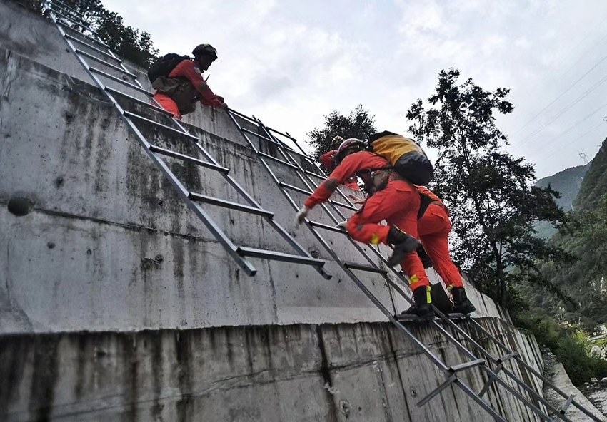 9月5日19時左右，消防員們呈一路縱隊，沿著搭建的鋼梯與繩索，手腳並用翻越山頭、大壩向震中挺進。華小峰攝