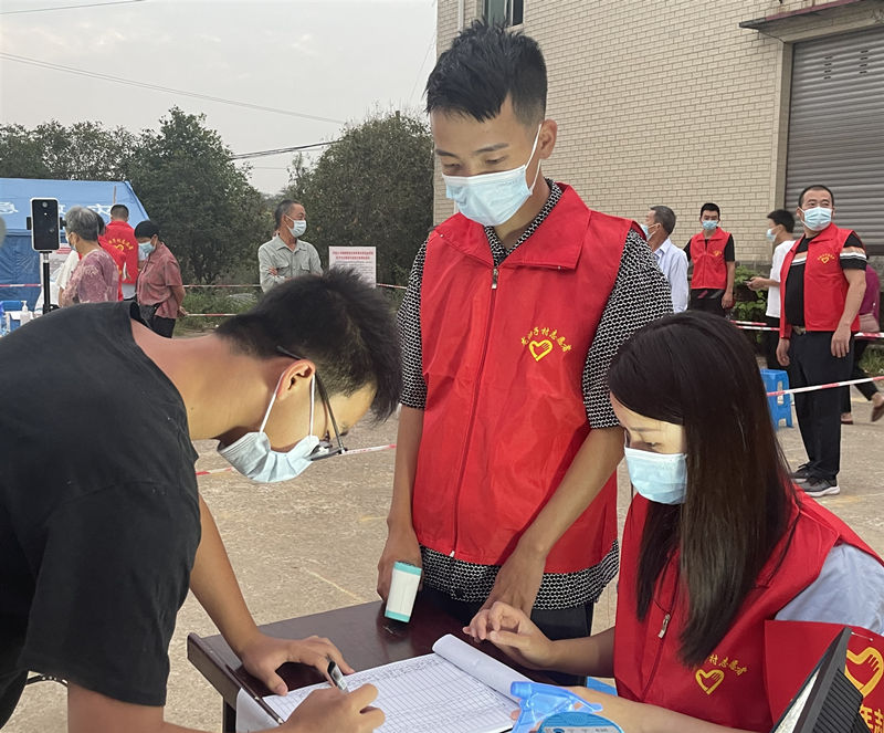 李佳在核酸检测入口处值守，为前来检测的居民进行测温登记。泸县供图
