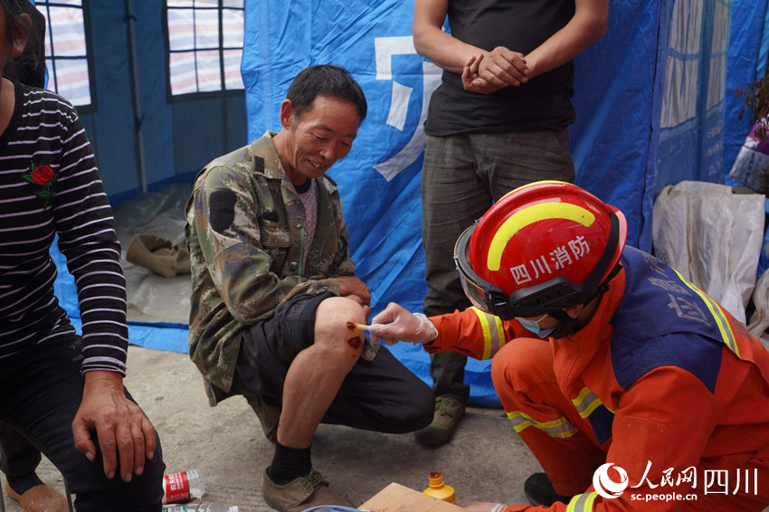 9月6日下午，救援人員徒步抵達與外界失聯的石棉縣幸福村，圖為一名消防員正用酒精和棉簽為老人擦拭傷口。李金珂攝