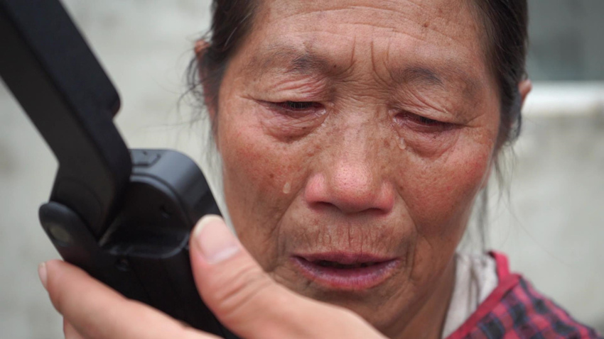 幸福村村民用衛星電話給家人報平安落淚。四川省消防救援總隊供圖