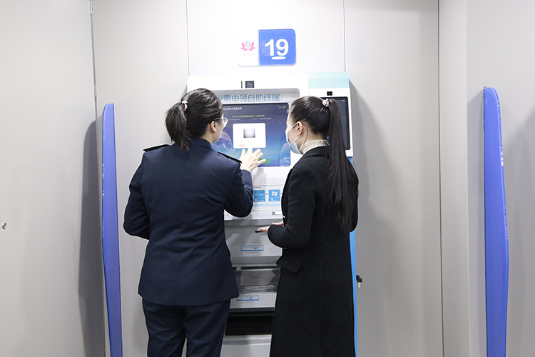 税务干部辅导纳税人在智能终端机办理业务。达州市税务局供图