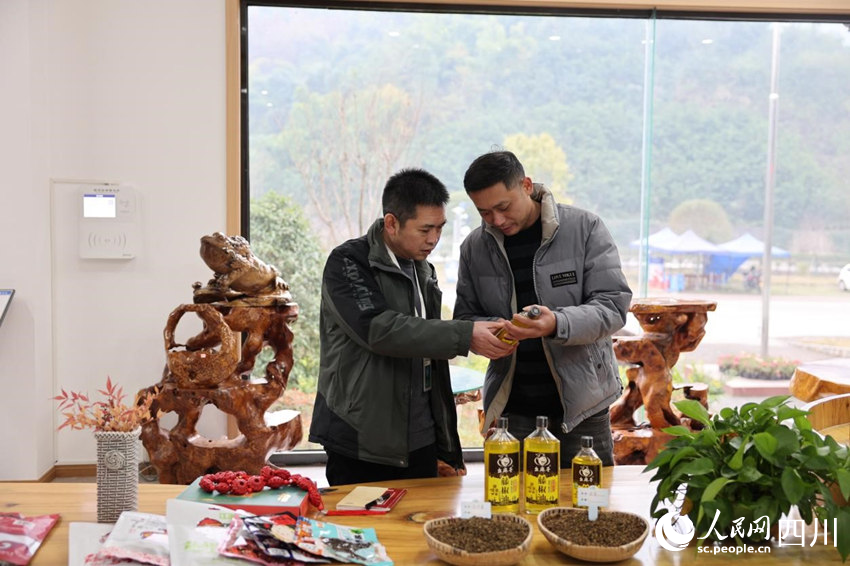 穆元奎（左）与李珏良探讨幺麻子藤椒油产品。卓雪摄
