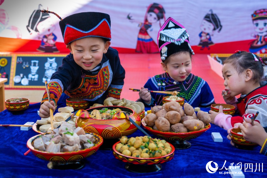 彝族年被称为“嘴巴的节日”，图为幼儿园内的小朋友们在品尝彝族传统美食。范艳民摄