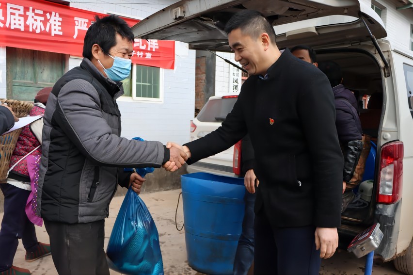帮扶干部为脱贫户分“过年鱼”。巴中市巴州区烟草专卖局供图