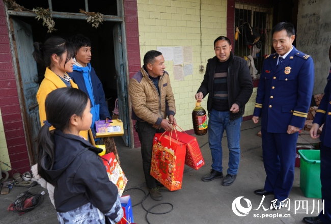 1月17日，在雅安市石棉縣王崗坪彝族藏族鄉愛國村，消防救援人員為正在看望慰問肖華平一家。李從林攝