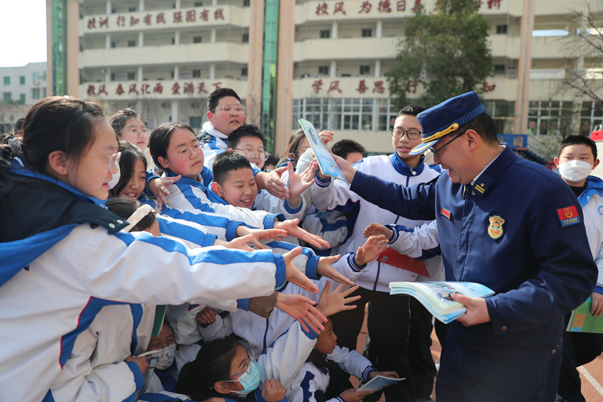 消防员正在给同学们发消防知识读本。广元市消防救援支队供图