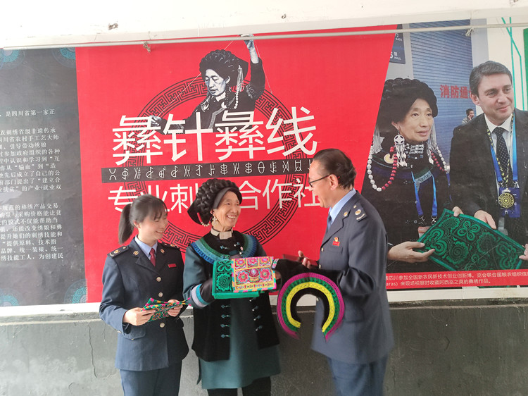 “彝绣”非遗传承人阿西巫之莫向税务干部展示手工作品。凉山州税务局供图