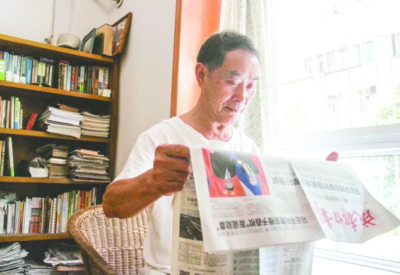 吴立寿在家看报纸。