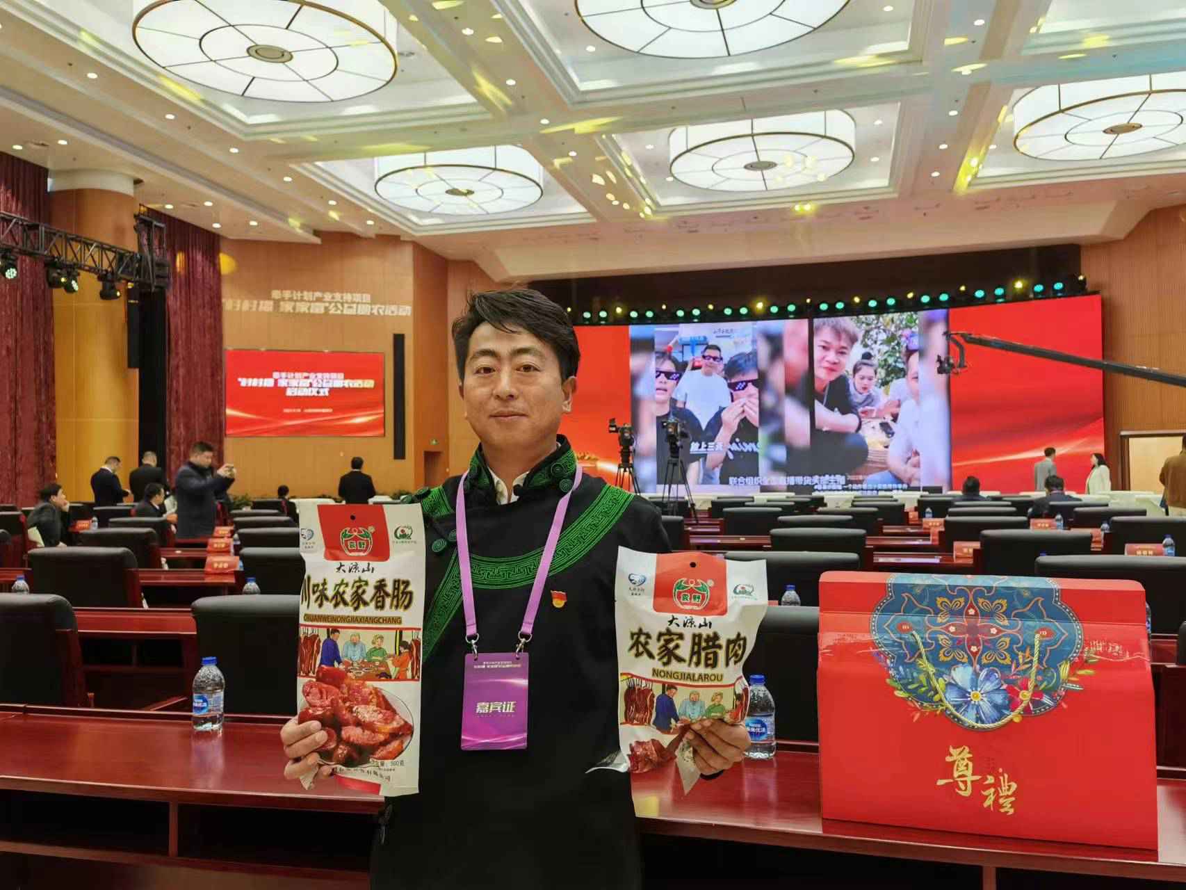 彝欣社区党委书记吉力阿体在现场展示本地特色产品。喜德县委组织部供图