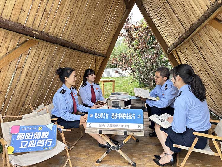 税务干部在农村看书，了解中国农村的巨大变化。成都市税务局供图
