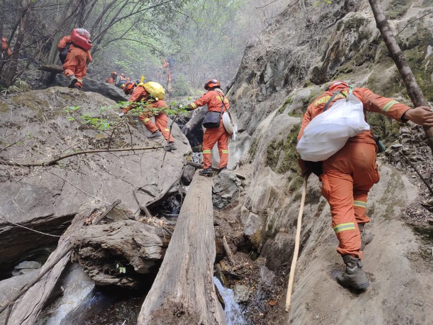 消防員背著滅火設備走過懸崖峭壁。四川森林消防總隊甘孜支隊供圖