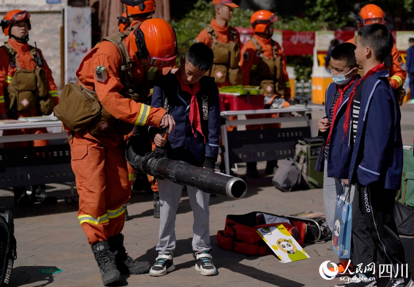 同學們在消防救援人員協助下親身體驗風力滅火機。彭科攝