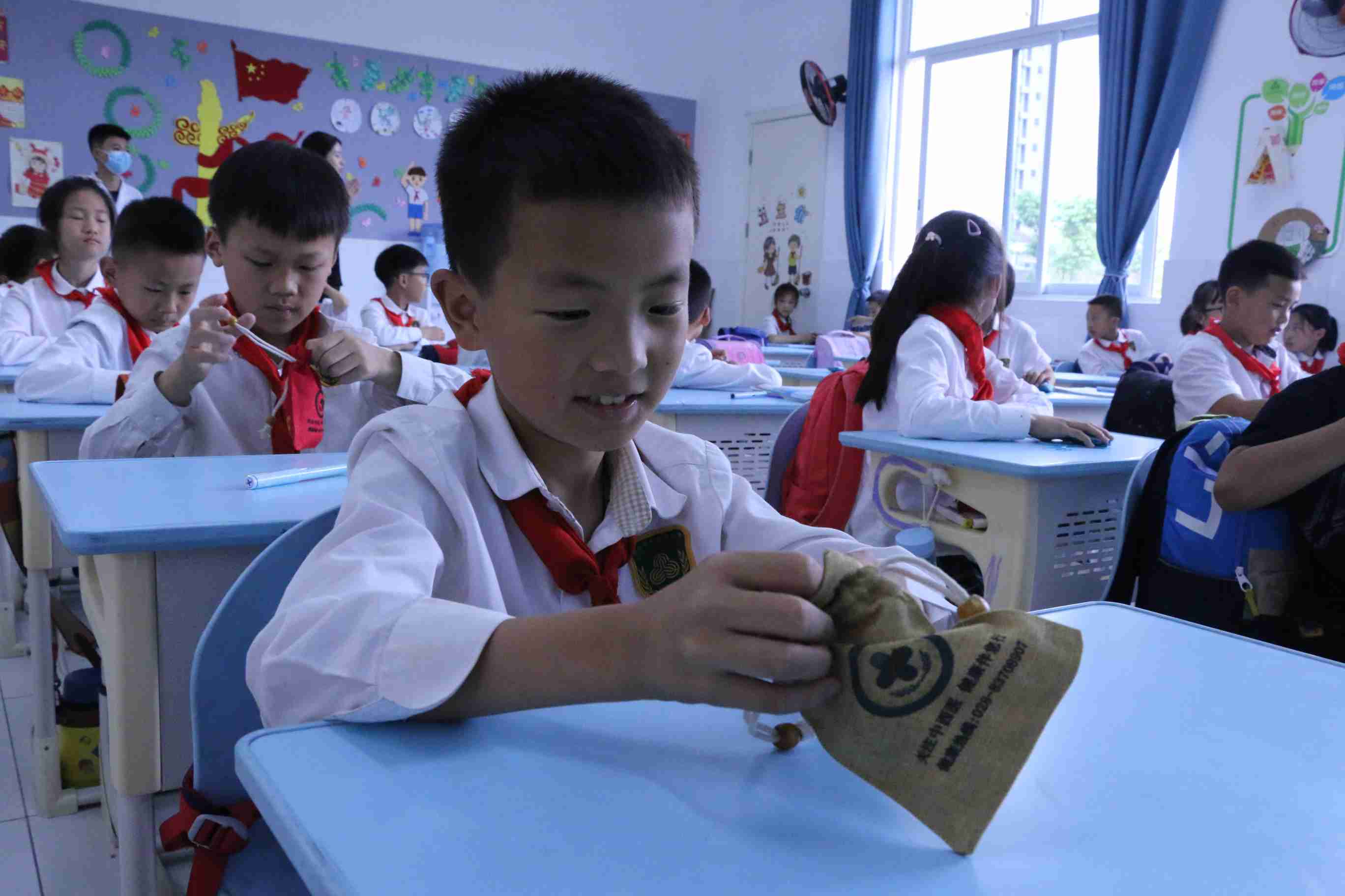 孩子们在医务人员指导下打开香囊，辨认中医药原材料。彭州市中西医结合医院供图