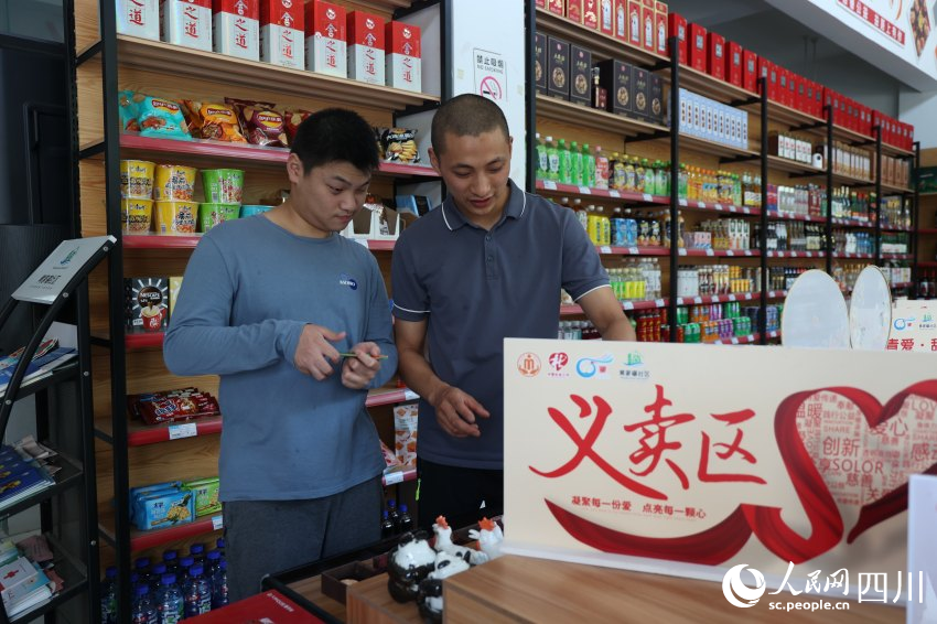 顾新（右）与小李在盘点义卖区货物。杨千依摄