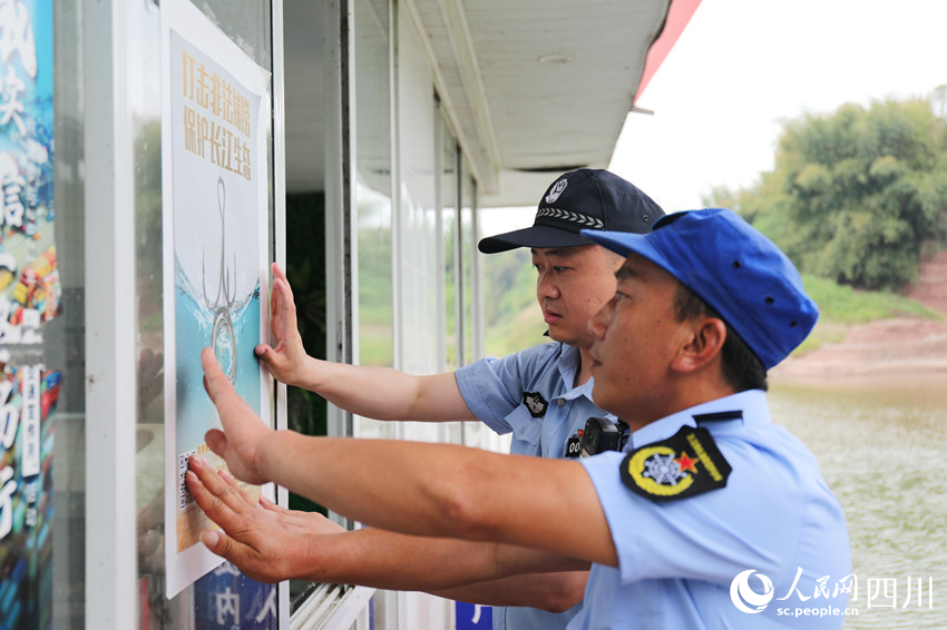 長江航運公安民警與漁政協助巡護隊員一同張貼“禁捕”宣傳海報。人民網 趙祖樂攝