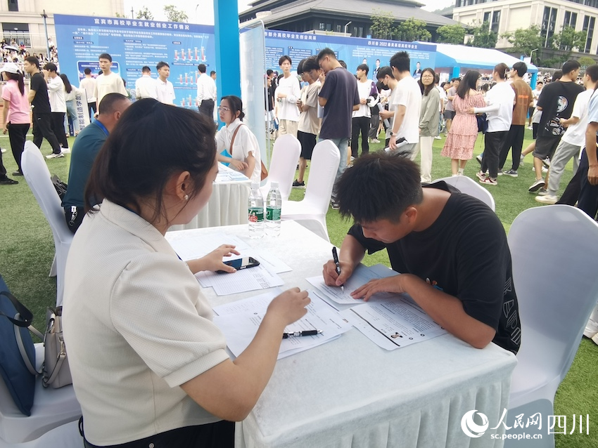 招聘会现场，求职毕业生在意向企业展台填写求职表。人民网记者 郭莹摄