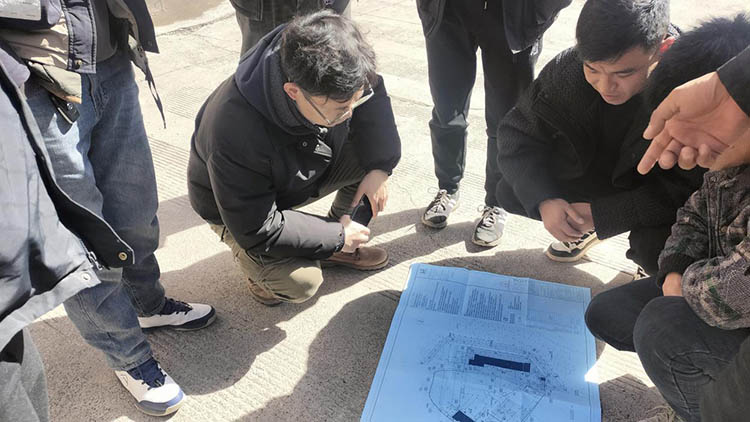 中铁信托调研组与乃通村小学改扩建工程项目人员交流并查看设计图纸。中铁信托供图