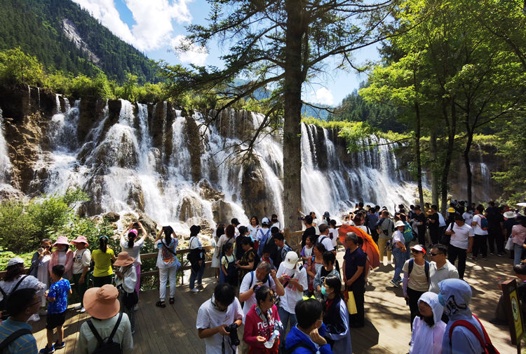 九寨沟景区内，游客在瀑布前拍照留影。九管局供图