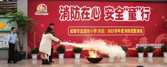 两位老师现场演示灭火器的操作，火盆里的熊熊大火瞬间被扑灭。学校供图