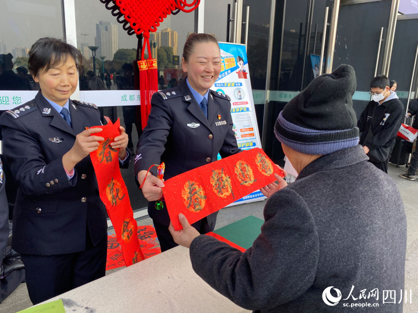 成都东站西广场，来往的旅客收到民警送出的对联。