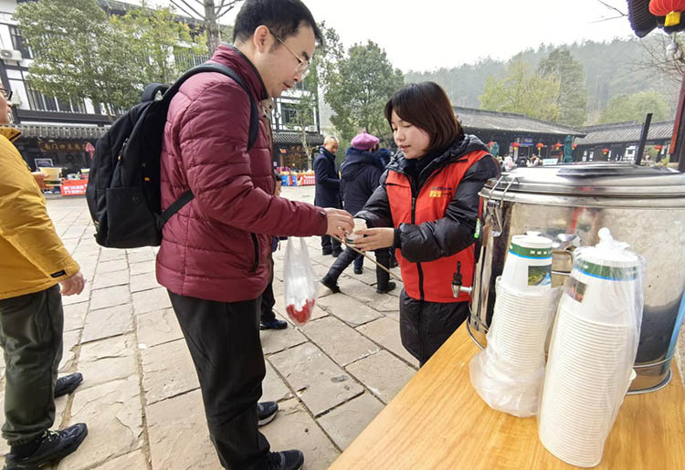 志願者正在為游客端紅糖生姜水。劍閣縣委宣傳部供圖