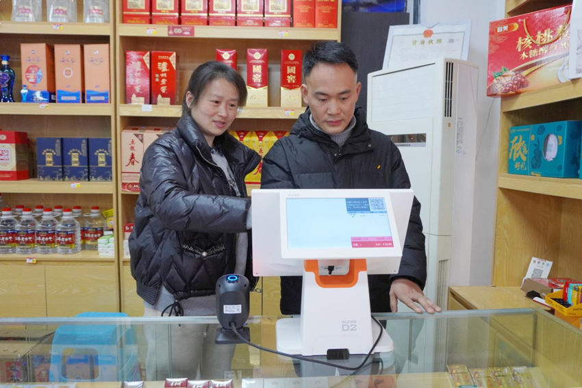 客户经理（图左）指导刘洪（图右）操作收银机。自贡烟草供图
